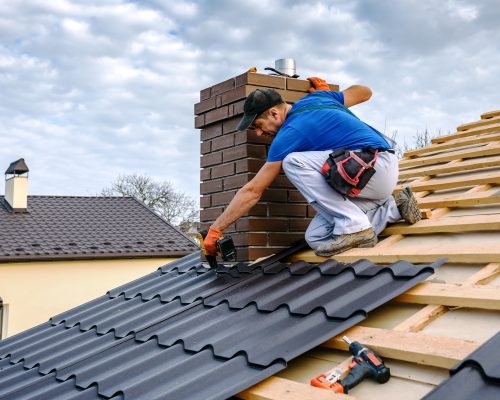 a professional master (roofer) with electric screwdriver covers repairs the roof
